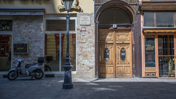 A street with a stone building, a wooden door, and a sign with a number. - Budapest Passage 1 (Budapest)