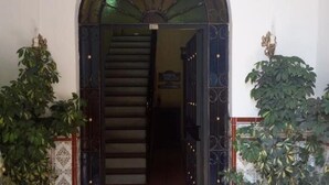 Una entrada empavedada con un arco, flanqueada por macetas con plantas, que conduce a una escalera.