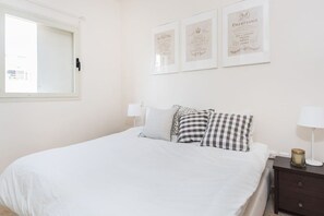 A bedroom with a bed, pillows, a nightstand, a lamp, and framed certificates on the wall. - Mamad Duplex • Terrace • 3m to Beach by SeaNRent (Tel Aviv)