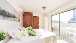 Hotellihuone, jossa on sänky, suuri ikkuna ja näkymä kaupunkiin.