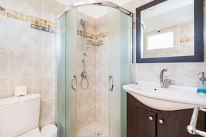 Un bagno con doccia vetro, lavandino bianco e specchio sopra.