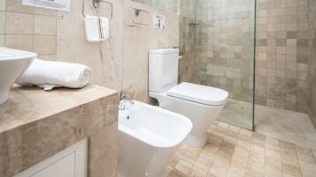 A bathroom with a toilet, bidet, and shower area.