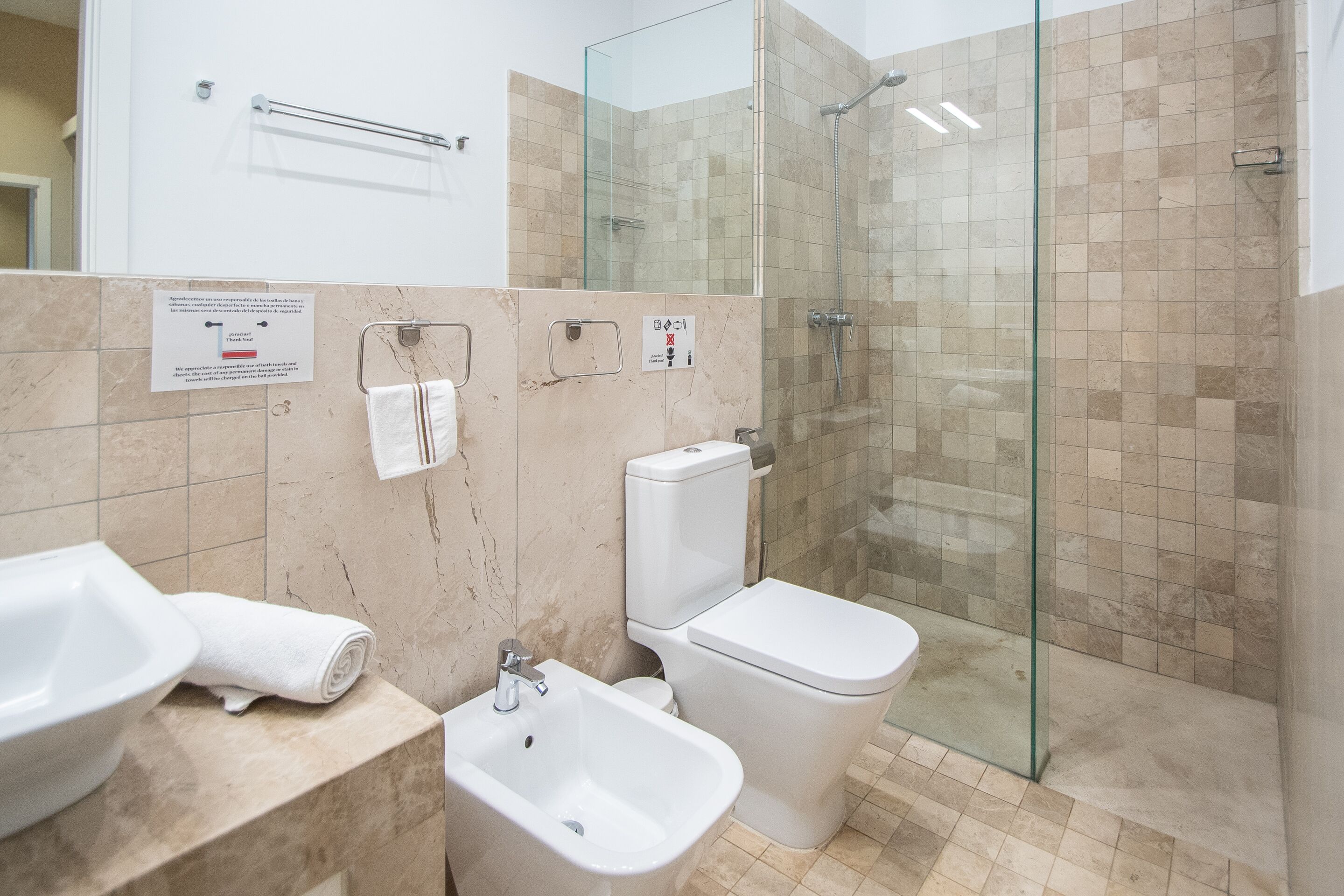 Une salle de bain moderne dotée d’une douche à parois de verre, d’un bidet et de toilettes.