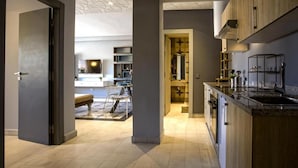 A modern kitchen with dark cabinetry, a central island, and a dining area with a bench and chairs. - BNB Medina (Marrakech)