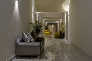 A modern hallway with a sofa, potted plants, and a patterned floor. - BNB Medina (Marrakech)