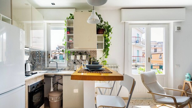 Cocina compacta con comedor, pileta y ventana con vista a edificios.