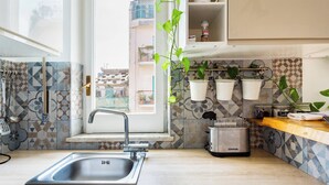 Una cocina con un lavamanos, un tostador y plantas colgantes.