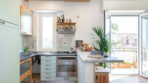 Cuina moderna amb forn de mur, fogó i finestra amb vista al balcó.