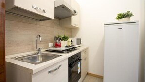 Una cocina compacta con un lavamanos de acero inoxidable, un microondas, una estufa y un refrigerador.