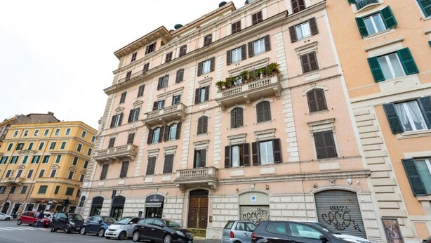 Un edificio de varios pisos con estilo arquitectónico clásico, que cuenta con balcones y una entrada a nivel de calle.