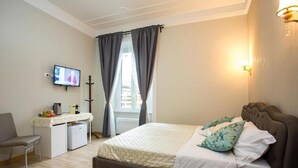 Habitación de hotel con cama, mesita de noche, lámpara y escritorio con silla.