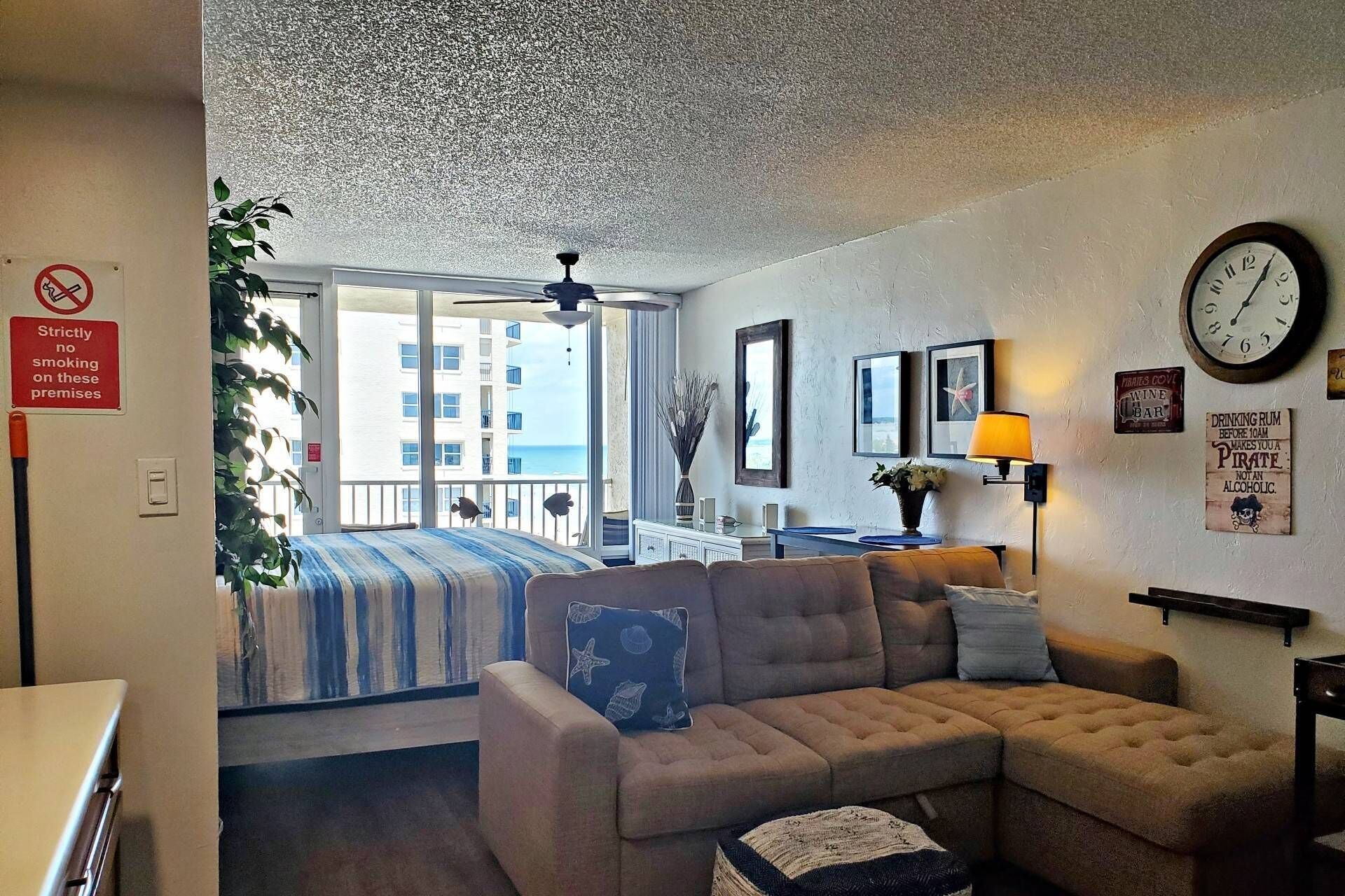 Une chambre avec un lit, un canapé, une horloge et une vue sur la mer.