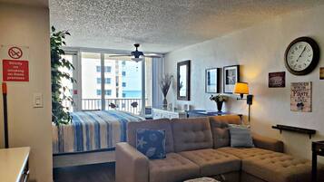 Une chambre avec un lit, un canapé, une horloge et une vue sur la mer.