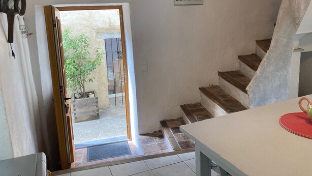 Una escalera que lleva al segundo piso, una puerta a un espacio exterior y un cuadro pequeño en la pared.