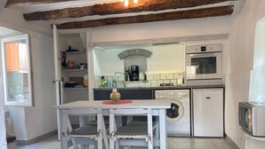 Una cocina compacta equipada con lavadora, microondas y un refrigerador pequeño.