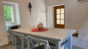 Un comedor con una mesa, sillas, una tetera, una ventana y una puerta.