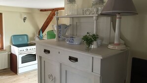 A kitchen with a white stove, oven, and a white cabinet with drawers. There are jars on the cabinet, a lamp, and a green container on the counter. - Apartment Büdnerei total up to 14 people (Auguste, Heinrich, Ida) (Stuer)