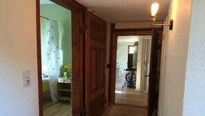 A hallway with wooden doors, a light fixture, and a sewing machine in the background. - Apartment Büdnerei total up to 14 people (Auguste, Heinrich, Ida) (Stuer)