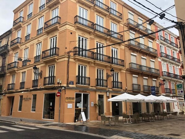 A multi-story building with balconies, outdoor seating, and a visible storefront. - You & Co. Quart Boutique Hotel (Valencia)