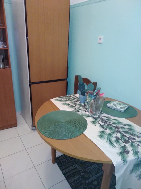 A dining area with a wooden table, green placemats, and a table runner with pine branches.