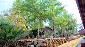 A stone wall with a pathway leading to a building with a red roof. - Macheke Lodges & Conference Centre (Macheke)