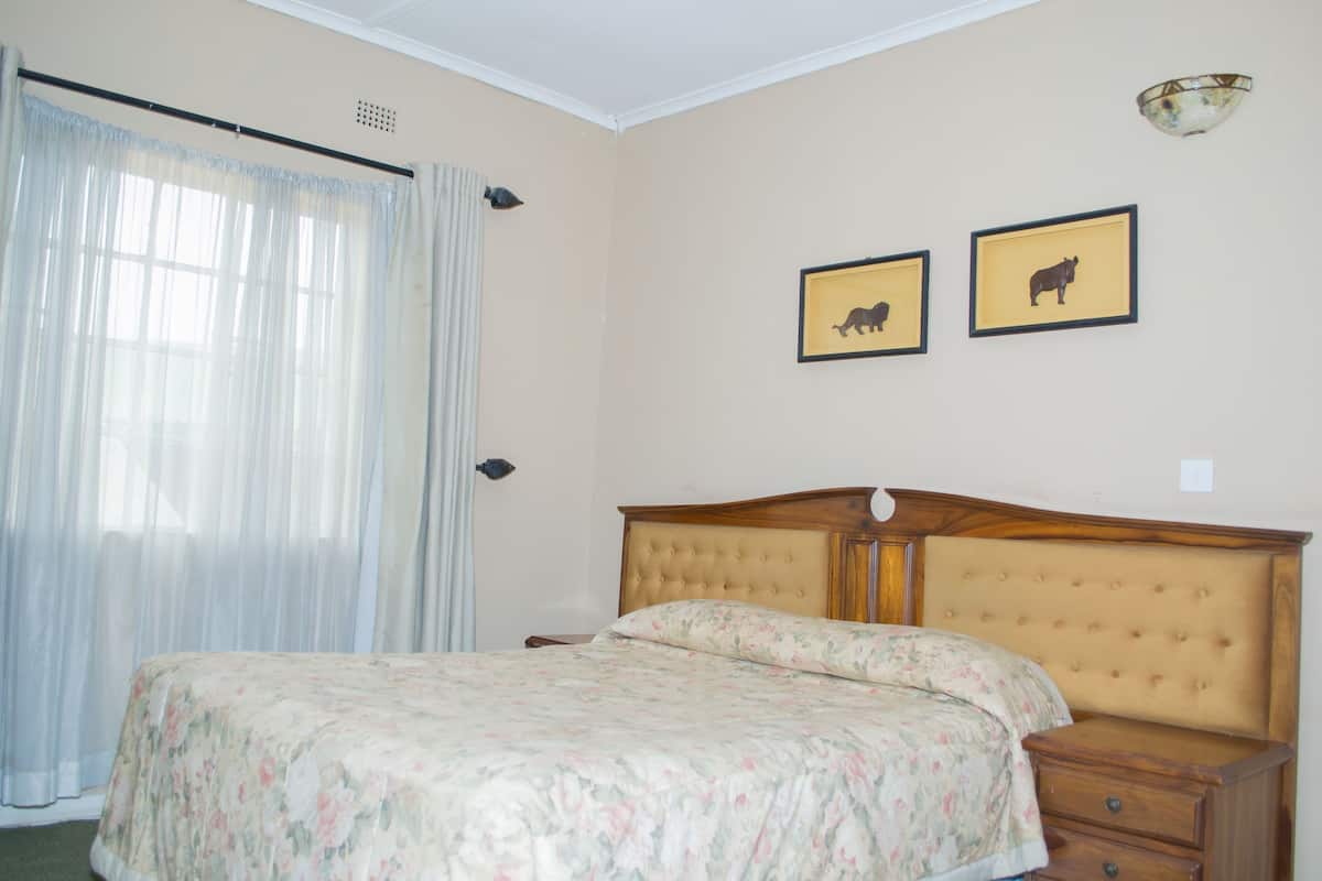 Ein Schlafzimmer mit einem Bett, einem Nachttisch, einer Kommode und zwei gerahmten Bildern an der Wand.