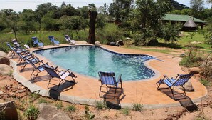 A swimming pool with lounge chairs around it, surrounded by trees and a building in the background. - Macheke Lodges & Conference Centre (Macheke)