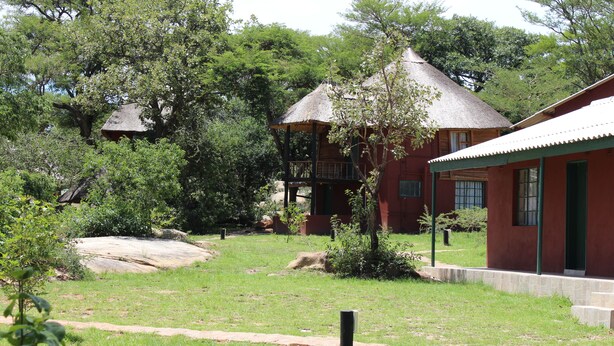 A rustic building with a thatched roof, surrounded by lush greenery and a clear sky. - Macheke Lodges & Conference Centre (Macheke)