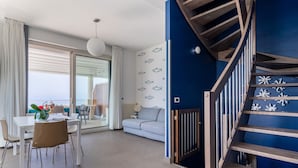 Ein modernes Wohnzimmer mit Essbereich, einer Treppe und Blick aufs Meer.