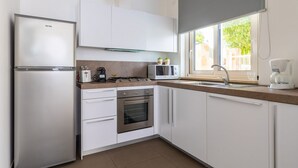 Eine moderne Küche mit weißen Schränken, einem Edelstahlkühlschrank, einer Mikrowelle, einem Herd und einem Spülbecken.