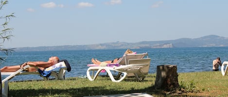 Privat strand, svart sandstrand och solstolar