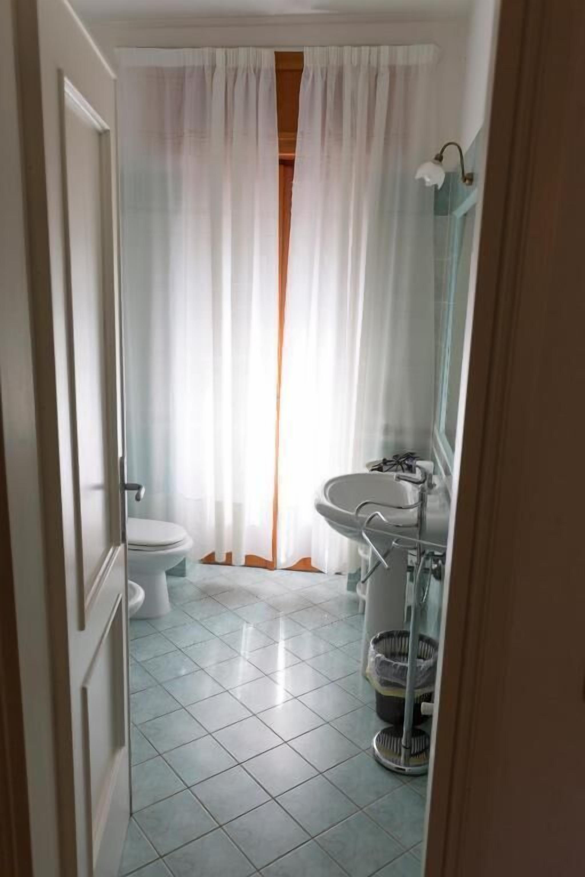 Une salle de bain avec des toilettes, un lavabo et un rideau de douche.