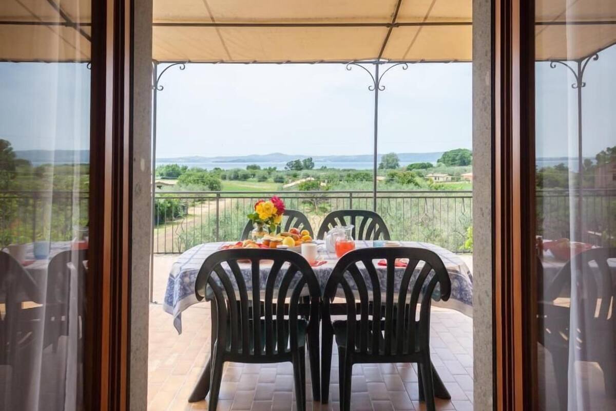 An outdoor dining area with a table set for two, chairs, and a view of the countryside.