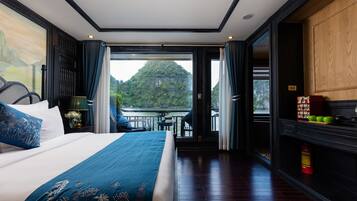 A bedroom with a large bed, a view of a lake, and a balcony with outdoor furniture.