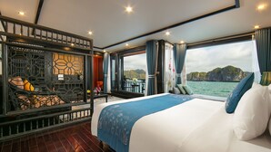 Une chambre spacieuse avec un grand lit, une vue sur l’eau et un balcon doté d’un espace salon extérieur.