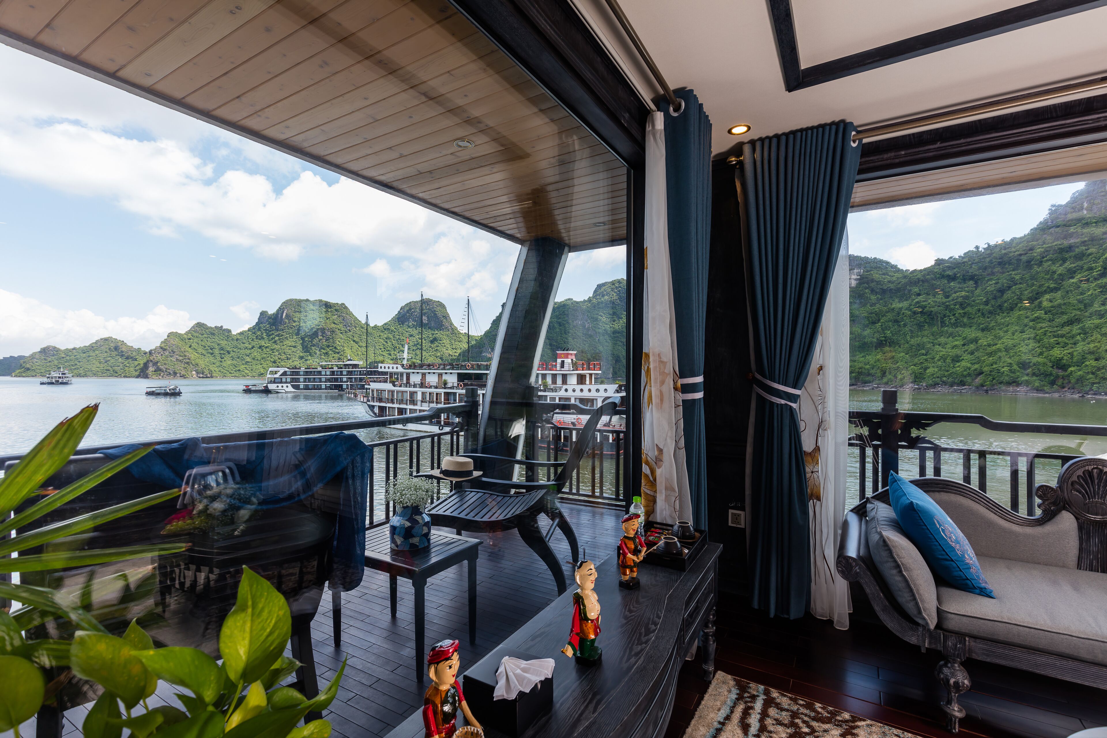 A deck with a view of a river and mountains, furnished with tables, chairs, and decorative items.