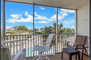 A balcony with a pool, chairs, and a view of a residential area.