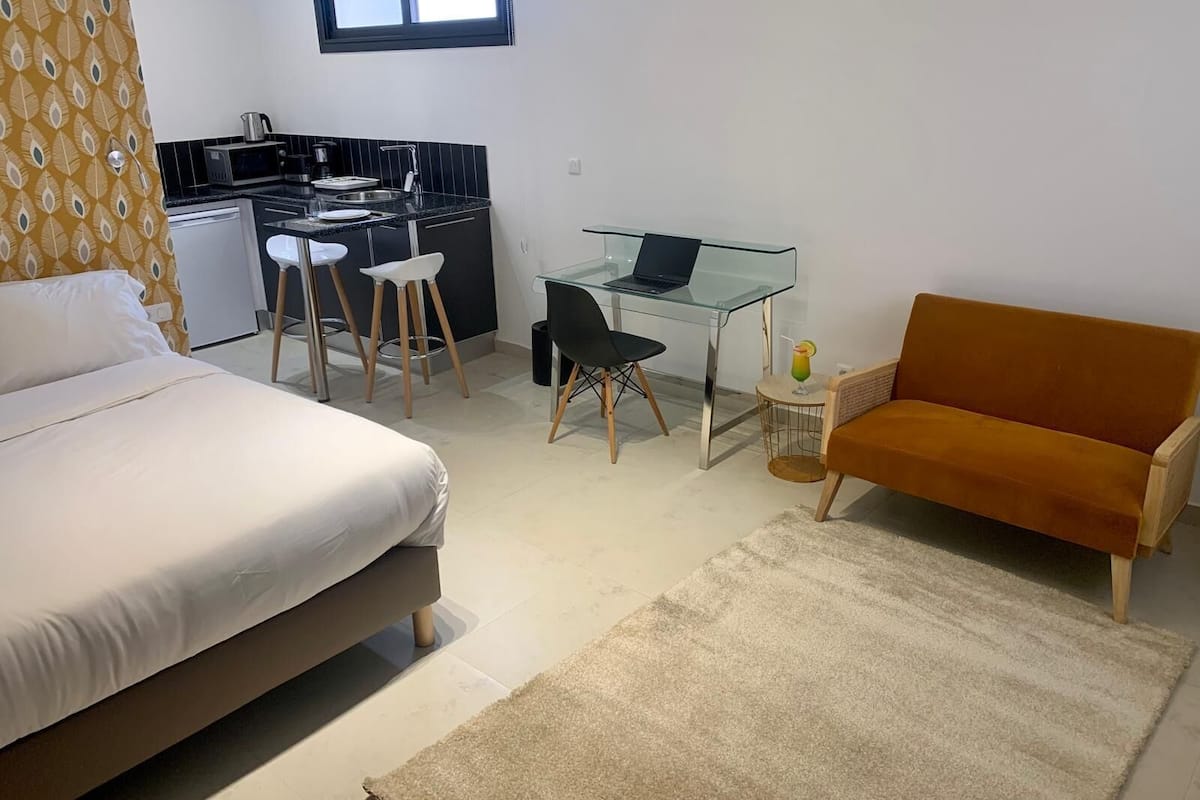 Un dormitorio con una cama, un escritorio con una computadora portátil, una silla y un sofá.