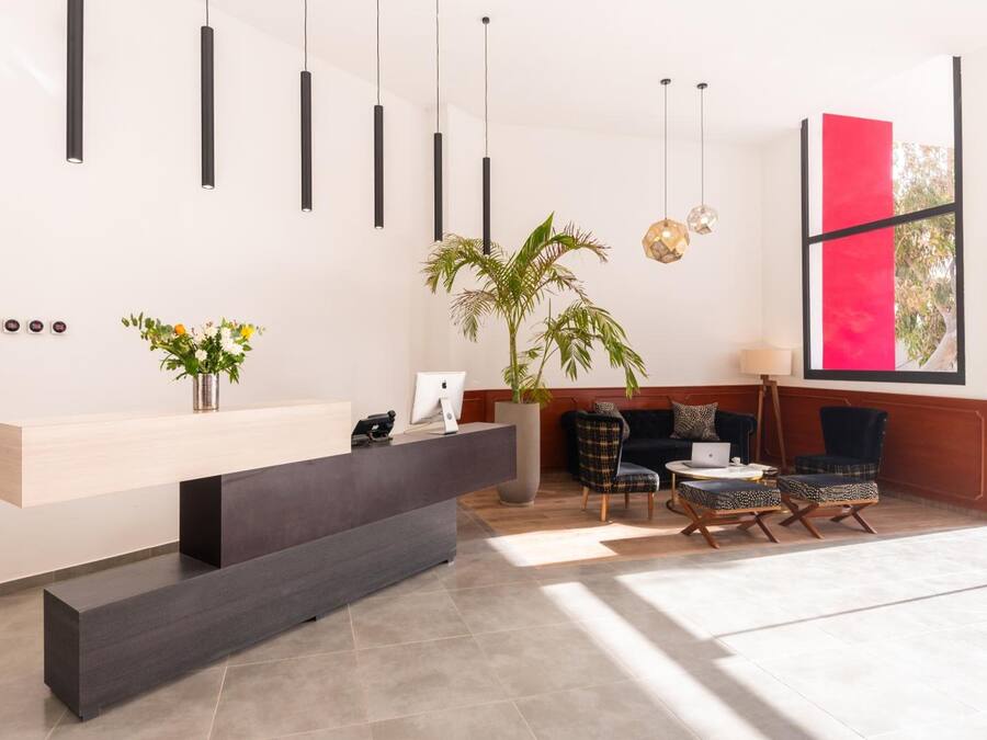 A modern reception area with a dark reception desk, a large potted plant, and a seating area with patterned chairs.