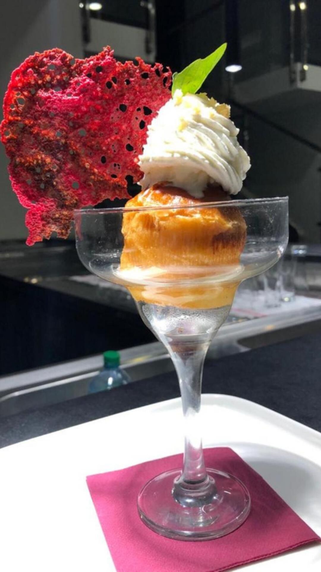 A dessert in a clear glass with a pink napkin underneath.