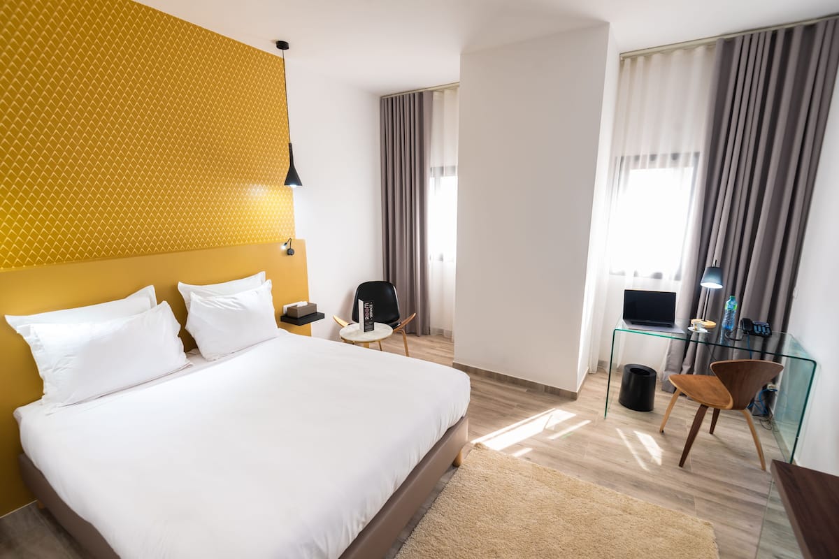 Una habitación de hotel moderna con una cama grande, un escritorio de cristal, una silla y un televisor.