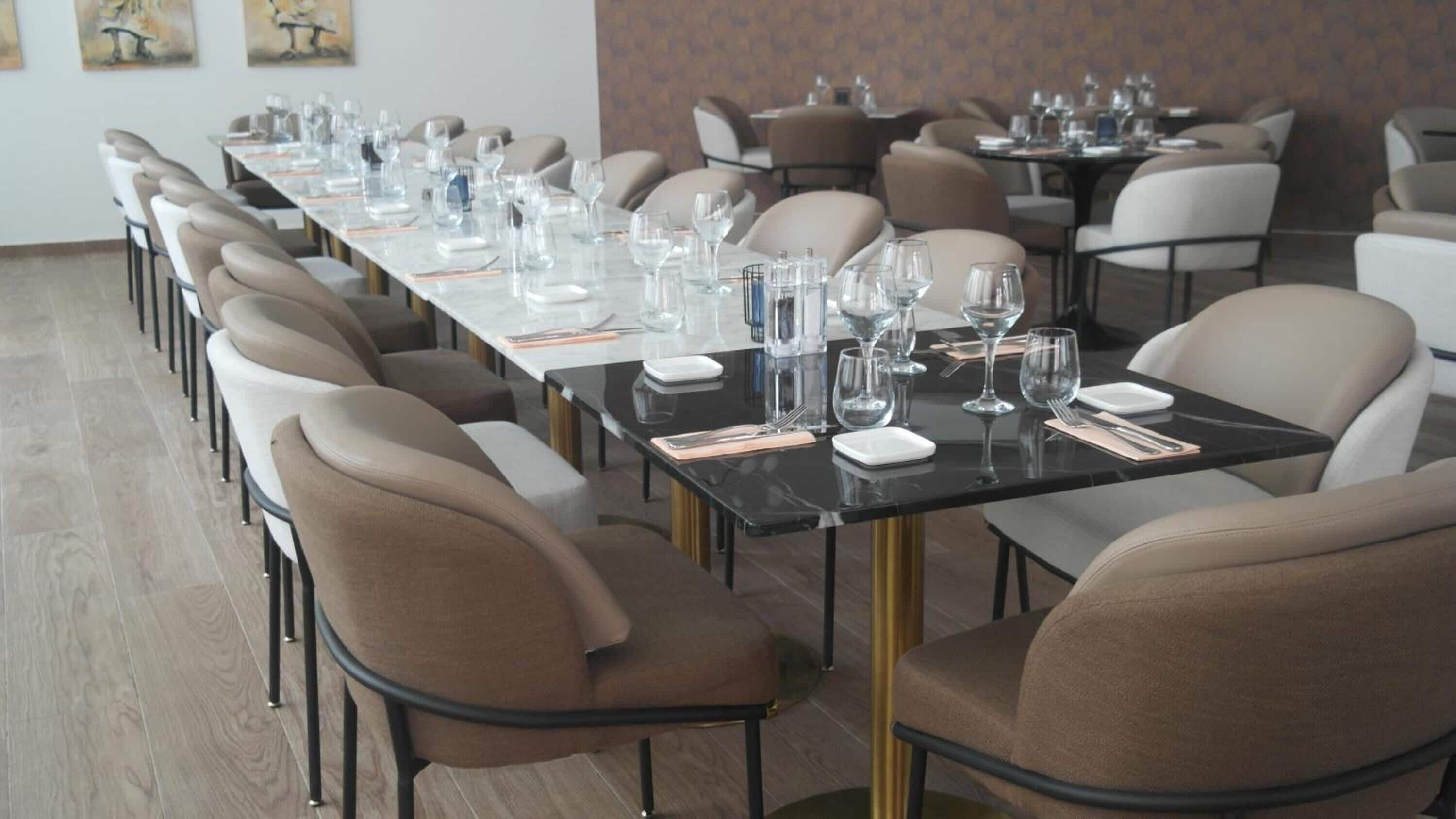 A conference room with long tables, chairs, and glassware set for a meeting.