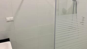 Un bagno moderno con doccia vetrata, lavandino bianco e pavimento piastrellato.