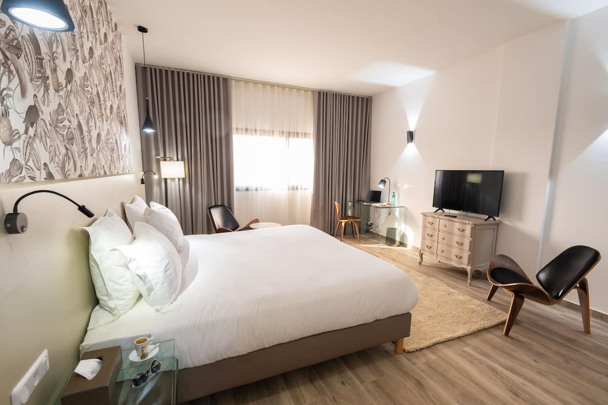 Habitación de hotel con una cama grande, un escritorio con silla, televisión y armario.