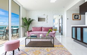 A modern living room with a sofa, coffee table, and a view of the sea. - Modern Grove Getaway | Walk to Peacock Park (Miami)