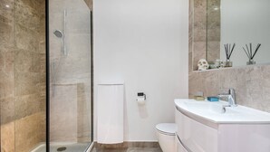 Un bagno moderno con doccia vetrata, un WC bianco e un mobile lavabo con lavandino e specchio.