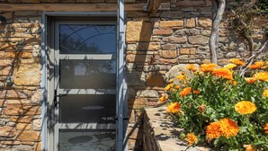 Een gebouw van steen met een glazen deur en een bloembed met oranje bloemen.