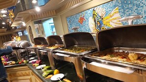 A buffet with various food items and a decorative wall with a mosaic design. - MS King Tut I Nile Cruise (Luxor)