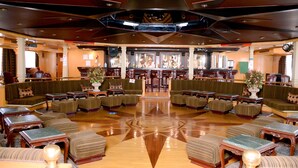 A spacious lobby with multiple seating areas, a central bar, and a polished wooden floor. - MS King Tut I Nile Cruise (Luxor)