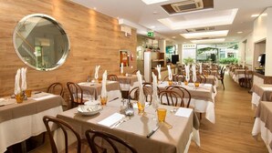 A restaurant with round tables, wooden walls, and a large mirror. - Hotel Albatros (Misano Adriatico)